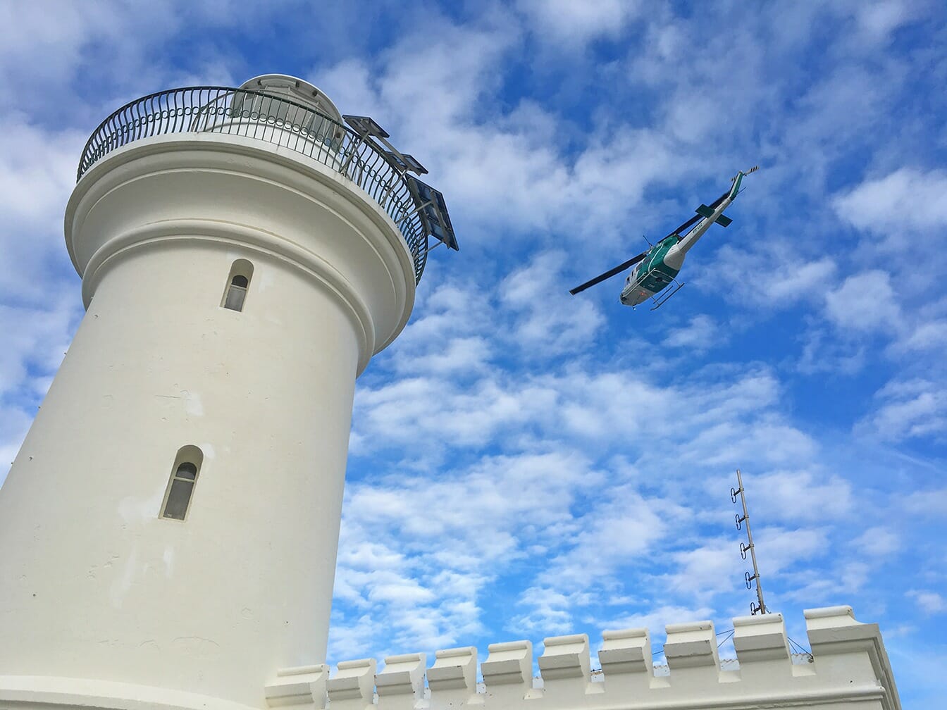 lighthouse with a helicopter in the background
