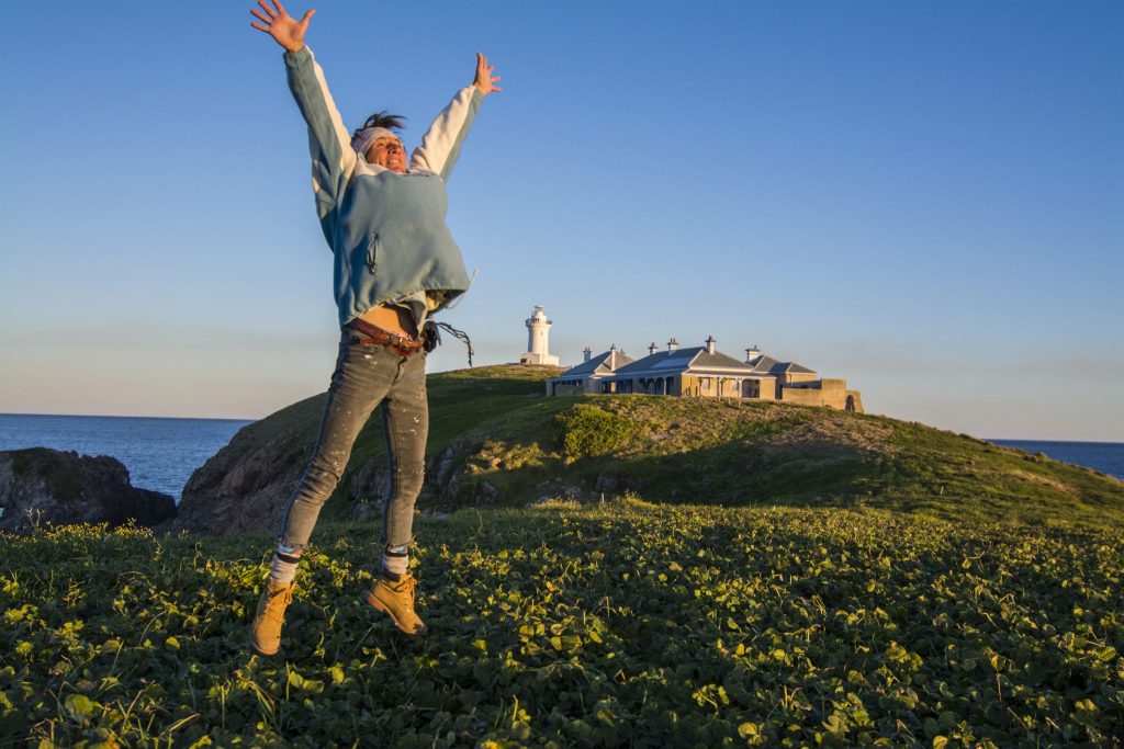 Happinesss! A visitor jumping in the air at the South Solitary Island in front of the lighthouse.
