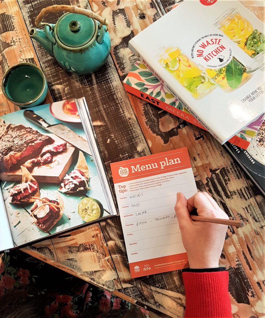 Person holding a pencil writing a weekly menu plan 