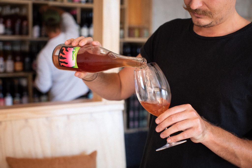 Close up of Max pouring a glass of natural wine at SLO Vino &