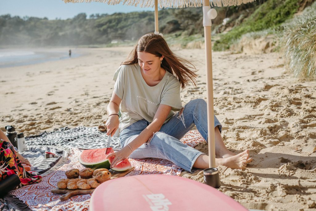 Chloe cutting watermelon on the beach