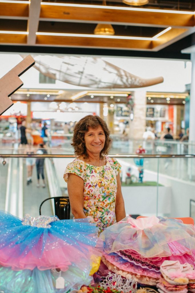A mid shot of a smiling woman with tutus in front of her