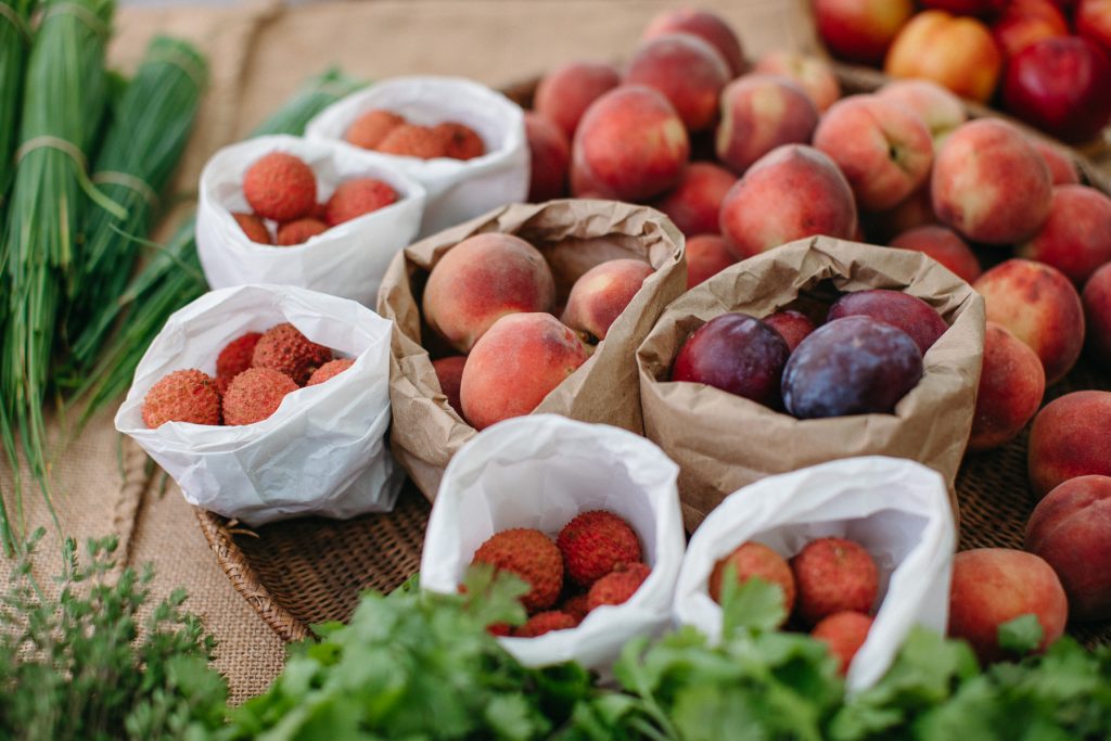 Lychees and peaches in paper bags on a table