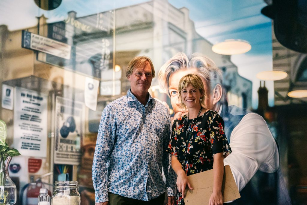 John Gowing and Ashleigh Frost in front of a portrait of David Wenham