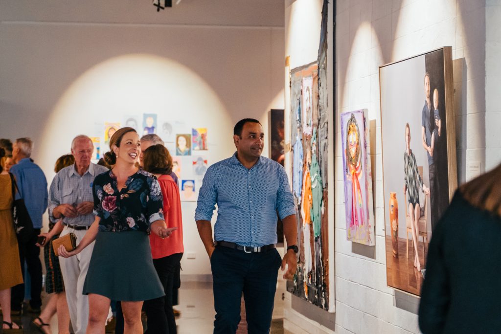A man and a woman walk through an art gallery 