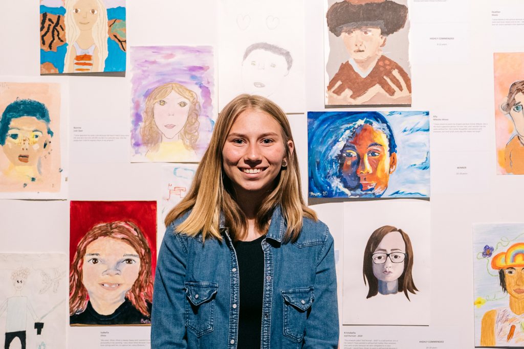 A smiling teenager girl in front of artworks