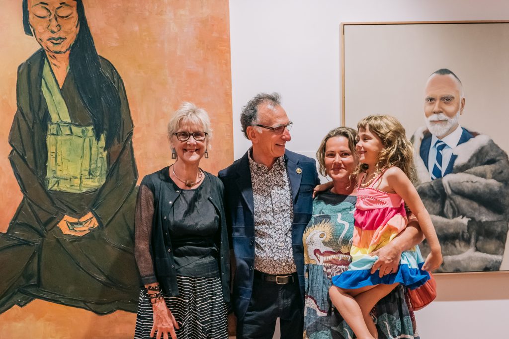 A group of four people standing in front of a large artwork