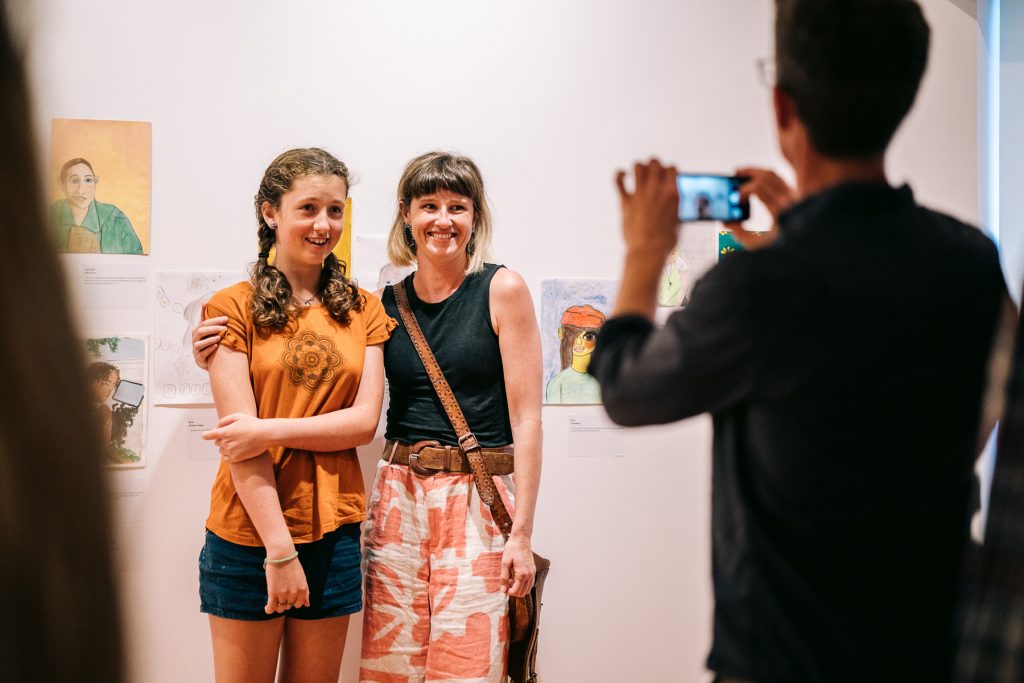 A teenage girl and her mother pose for a phone photo