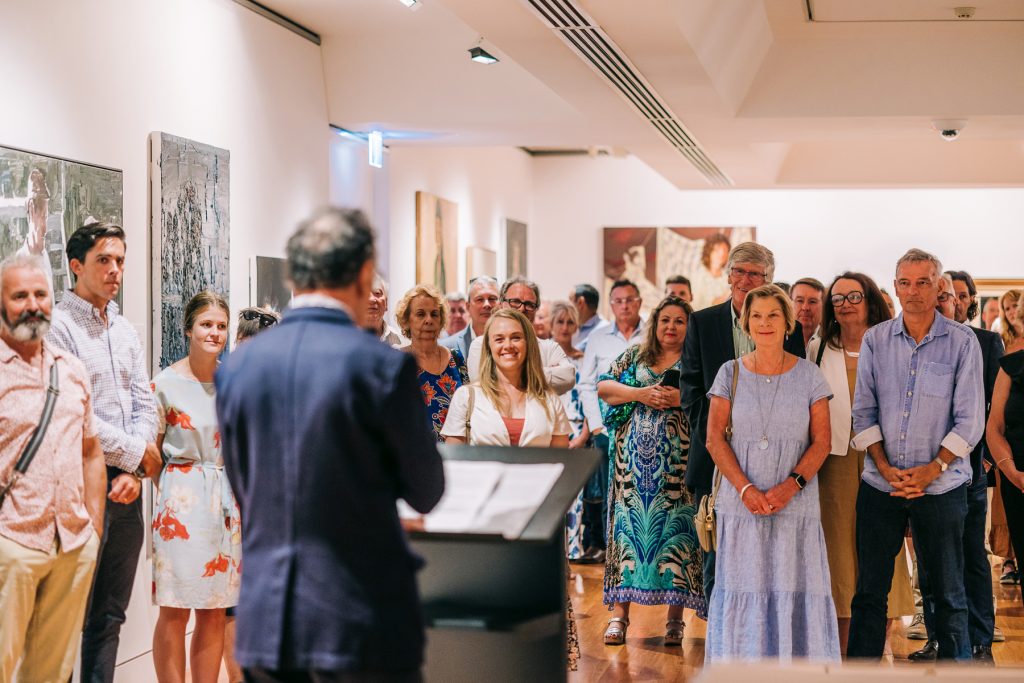 Tony Costa addresses a crowd at art exhibition opening 