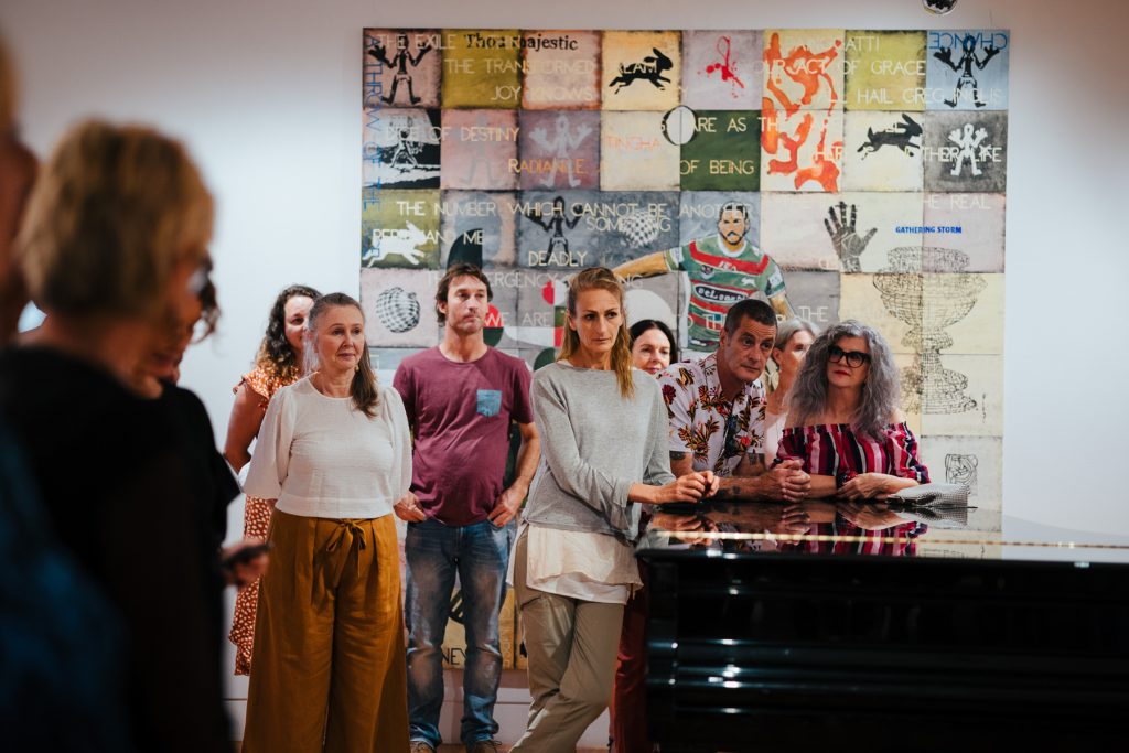 Group of people listening to speeches at art exhibition opening .