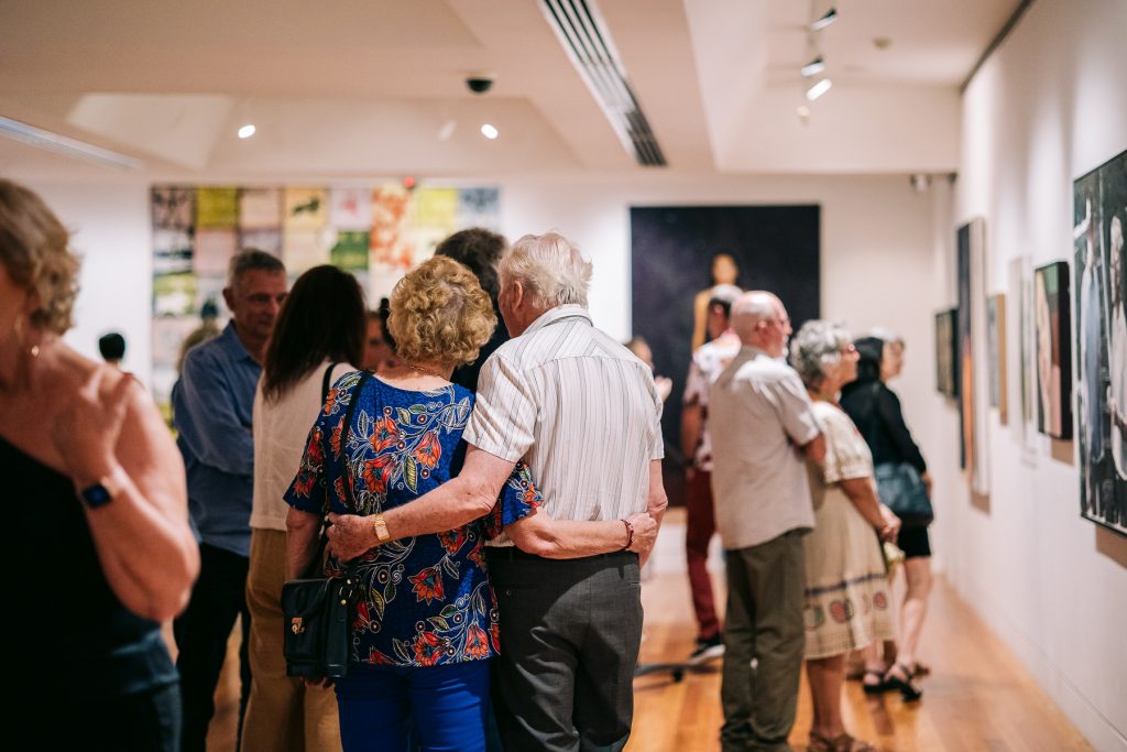 Old couple arm in arm at art exhibition opening 