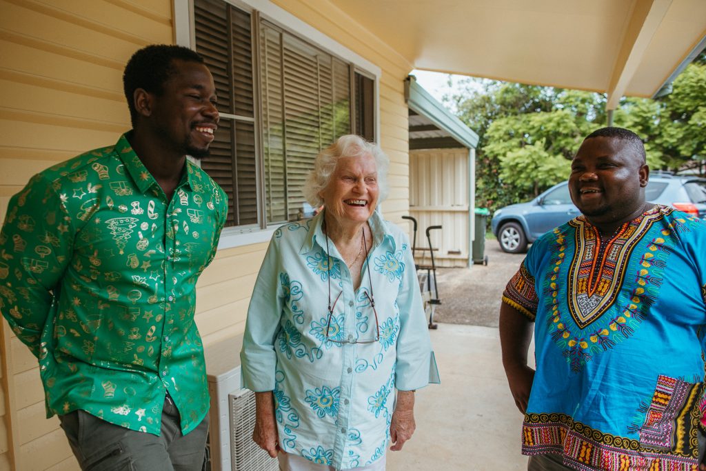 Two young men and one elderly woman standing together and smiling. 