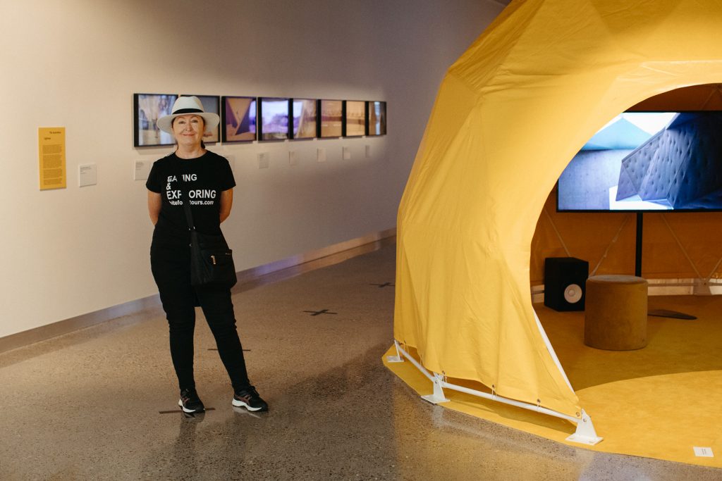 Awia Markey at the Coffs Central Culture Hub standing in front of Eugenia Lim's exhibition The Ambassador