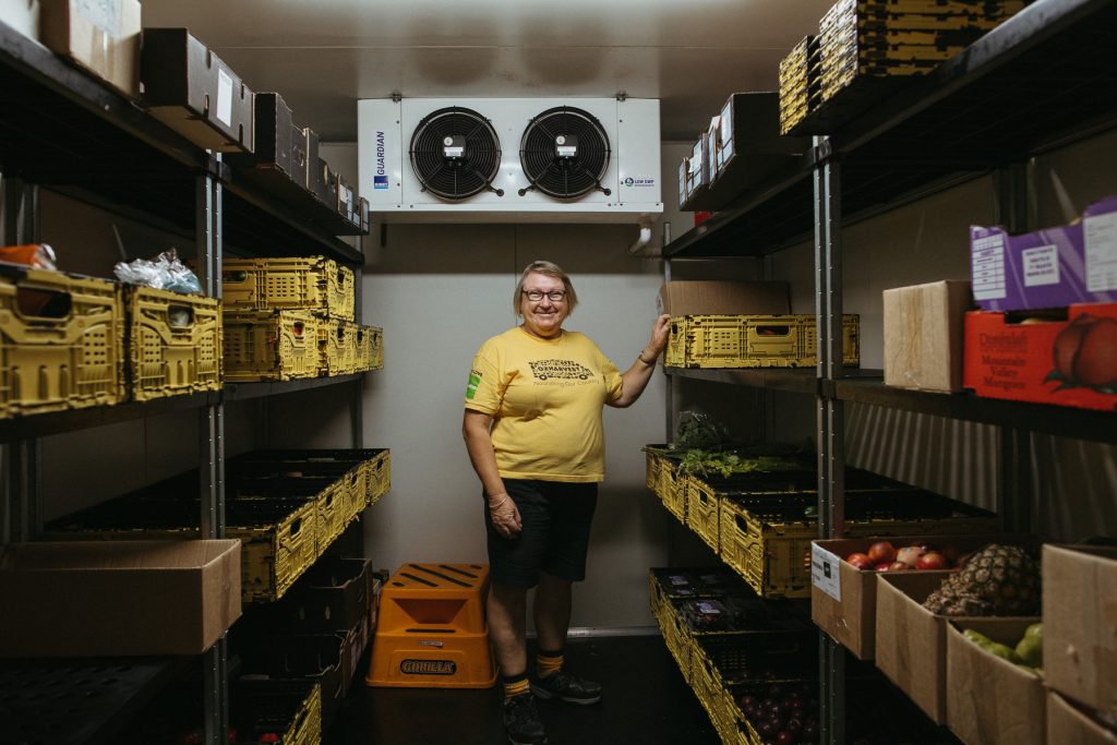 Julie Ferguson standing in the OzHarvest cool room surrounded by food