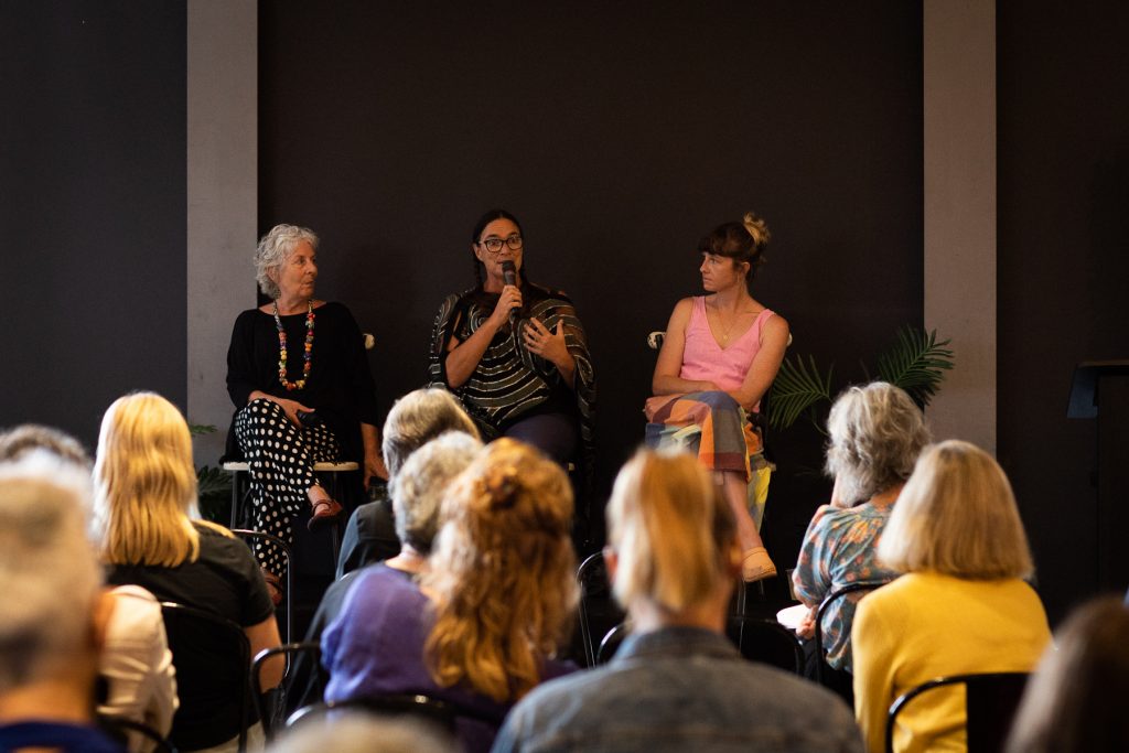 A panel of three women sitting in front of a crowd