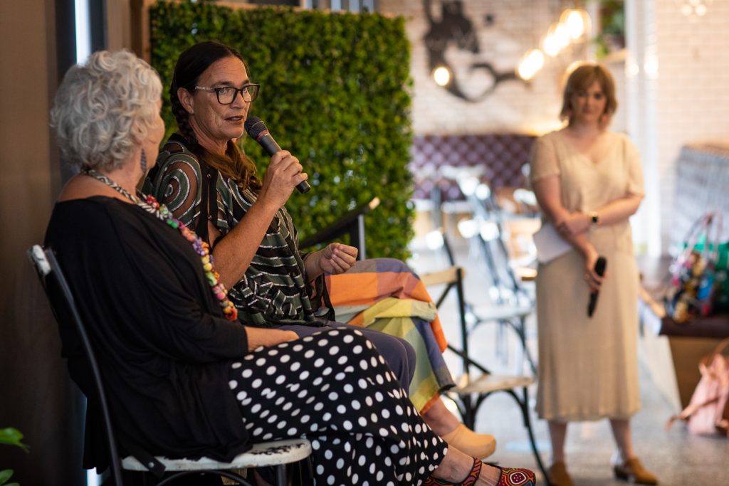 A woman speaking into a microphone as others look on