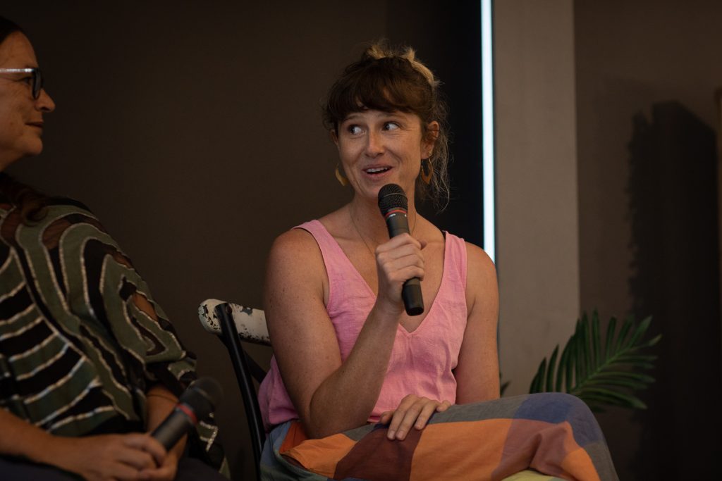 A woman smiling as she speaks into a microphone