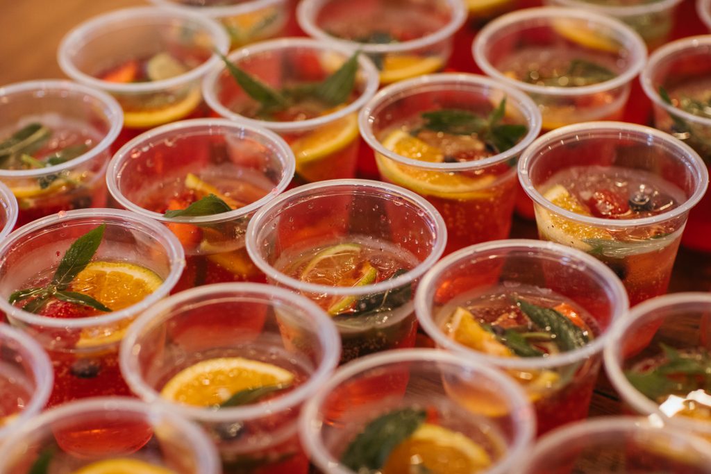 Plastic cups full of pink liquid, mint leaves and lemon slices