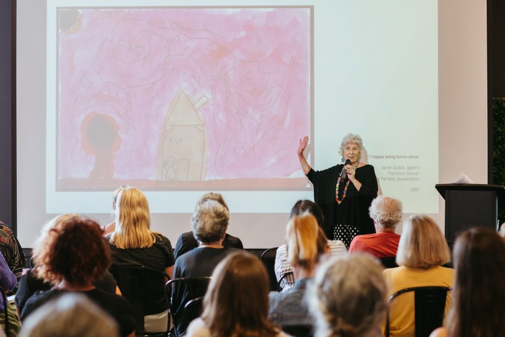 Wide shot of a woman presenting a lecture in front of a crowd