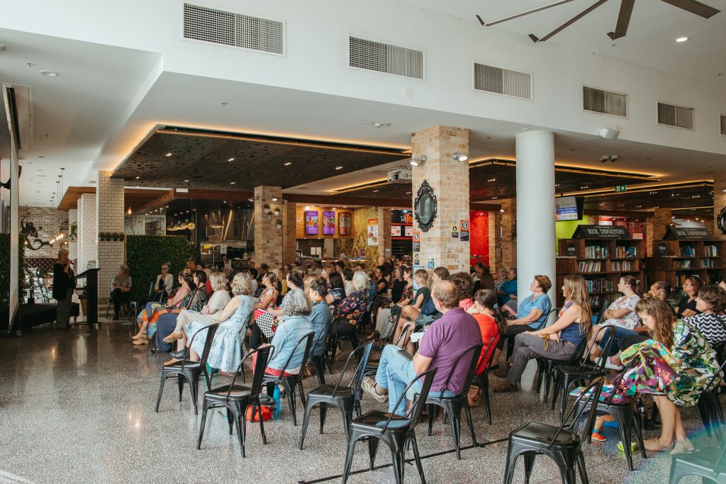 Wide shot of a large crowd sitting down listening to a lecture