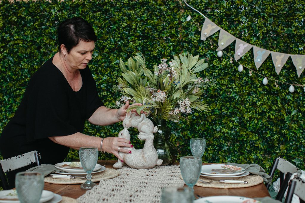 A woman placing a small rabbit sculpture on to a table