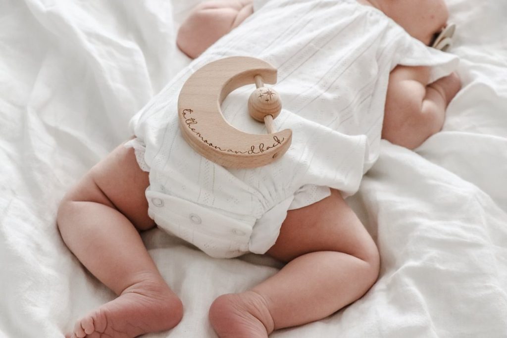 Close up of a sleeping baby wearing a white romper suit