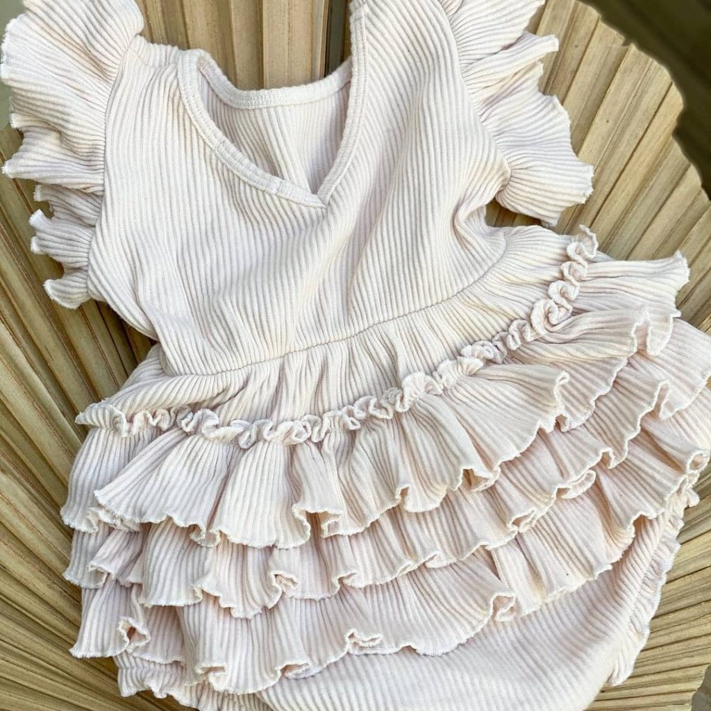 Close up of a frilly white romper suit for a baby