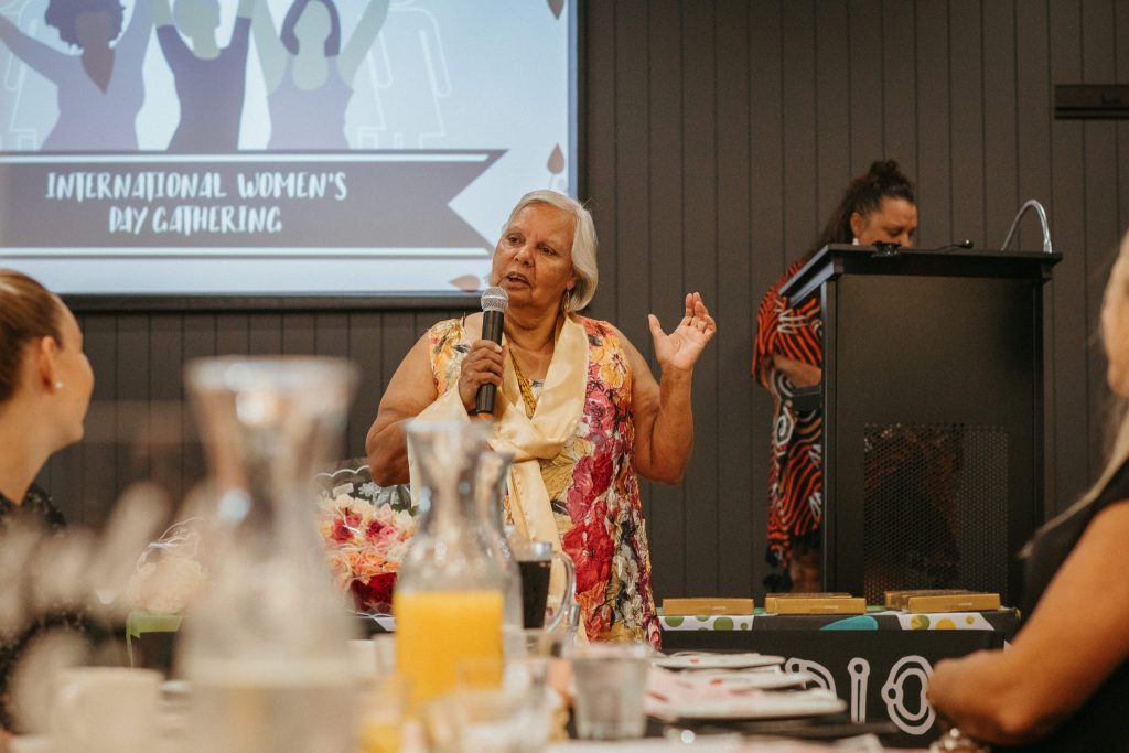 A older woman speaks in front of a crowd