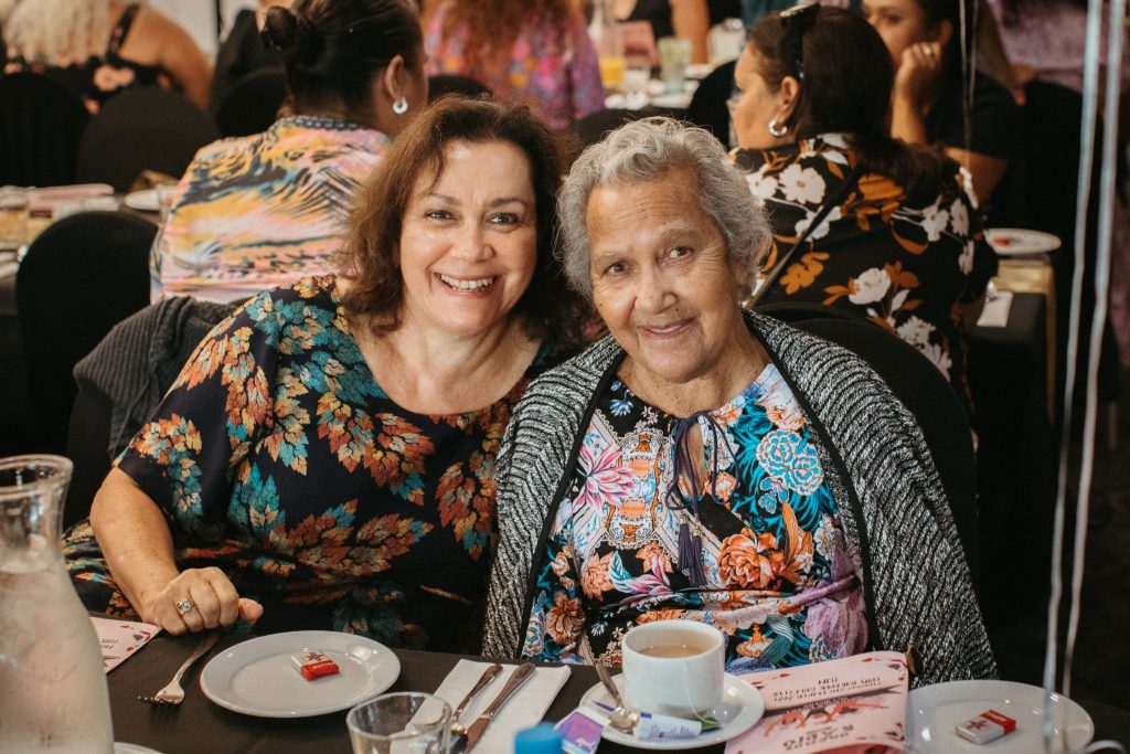 A elderly mother and her middle aged daughter smiling