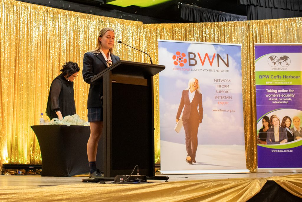 A teenage girl speaking into a microphone at a podium