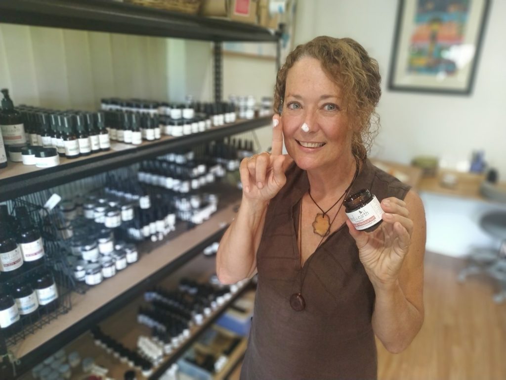 A smiling woman holding a jar of face cream 