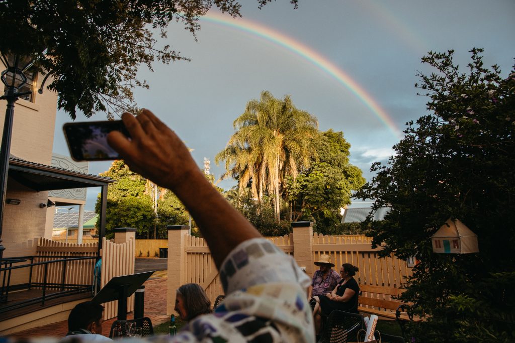 A person taking qa photo of a rainbow with their phone 