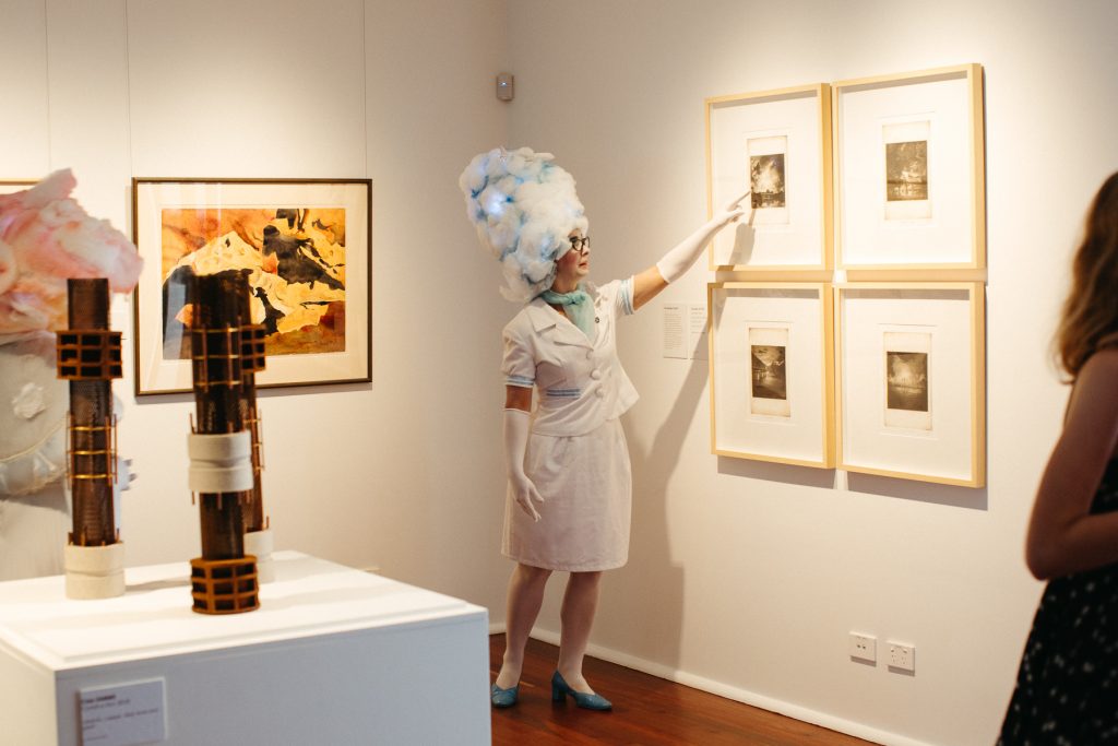 A woman pointing at an art work in a gallery 