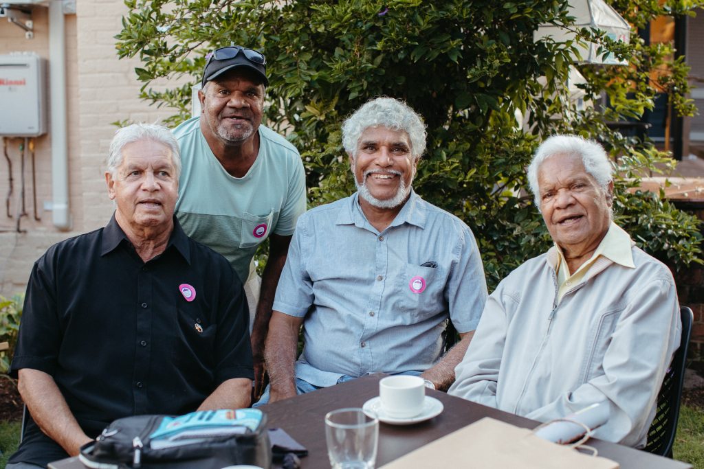 A group of four Aboriginal men smile and look at the camera