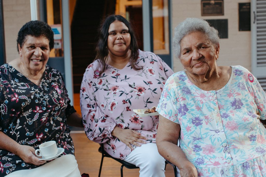 Three Aboriginal women smile and look at the camera