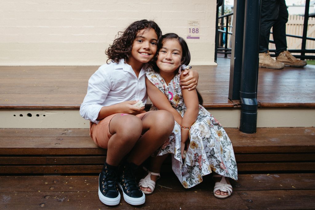 Two young children embrace and look at the camera