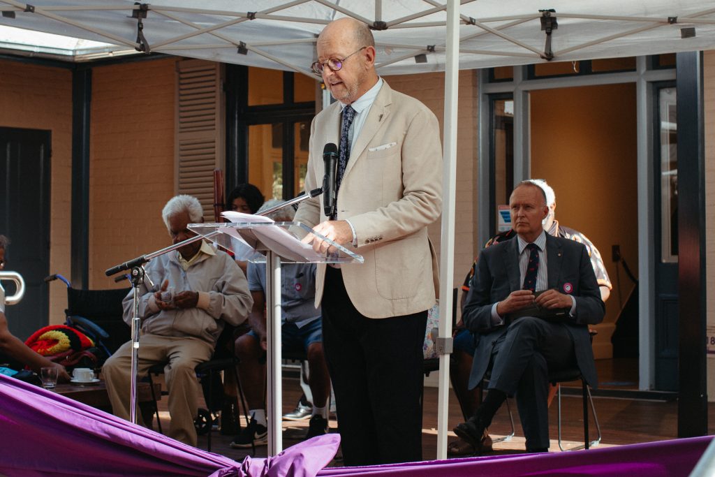 Executive Director Arts Northern River Peter Wood stand at a podium in front of a crowd