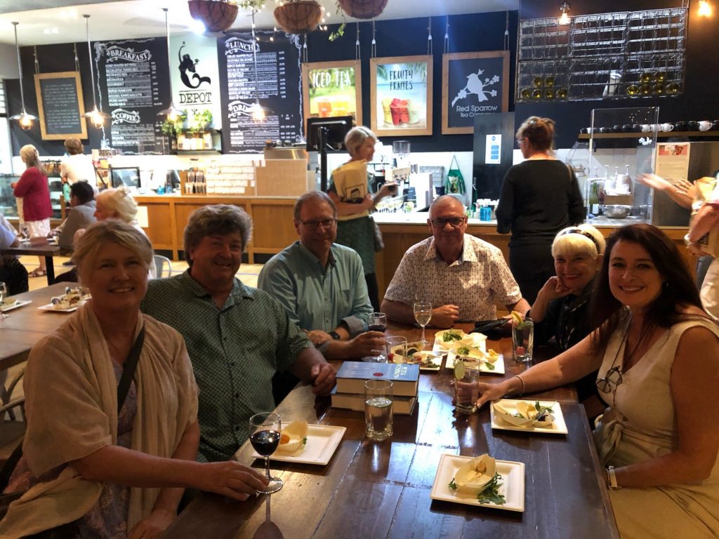 A smiling group sits around a table with food and drinks