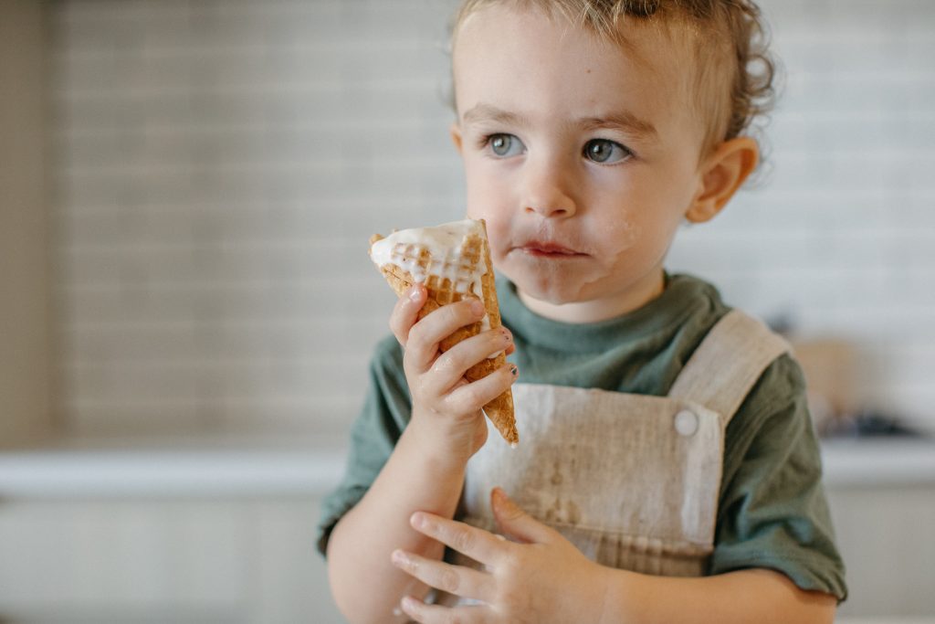 A toddler holding a melting ice cream 