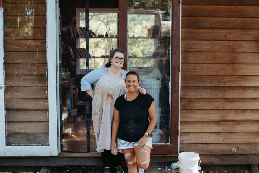 Two women standing in front of a wooden cabin