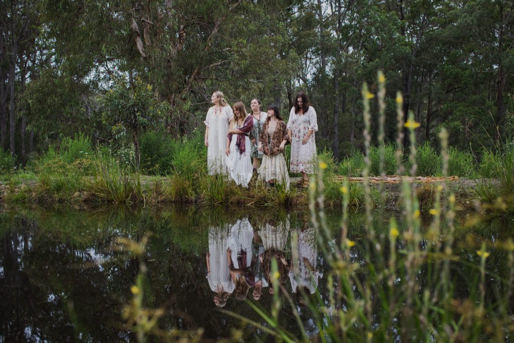 A group of young women stand beside a dark dam