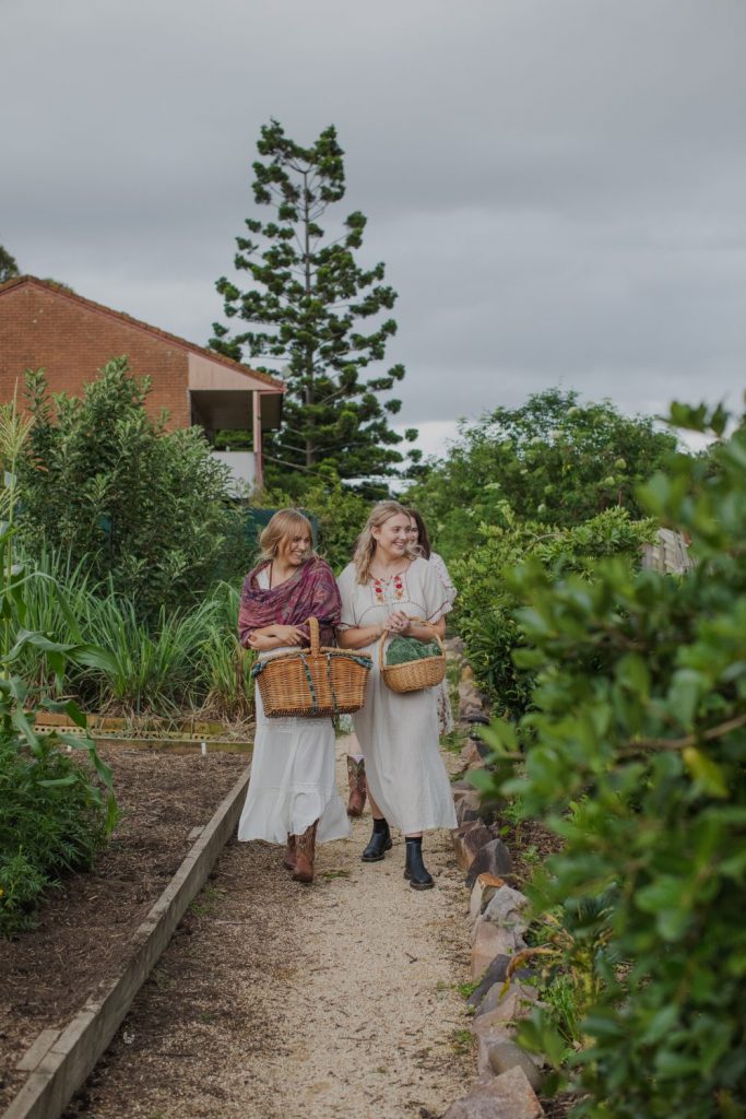 Young women holding picnic baskets walking through a garden