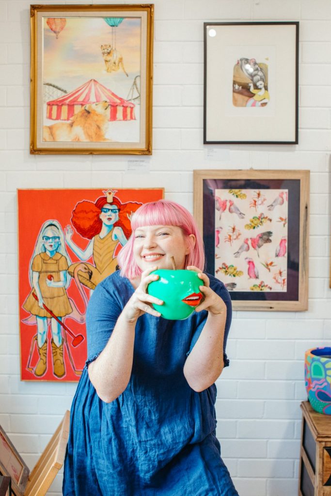 A woman with pink hair smiling at the camera