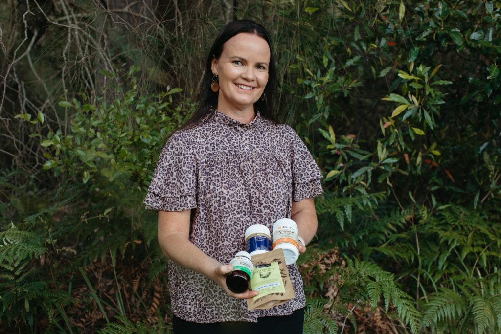 A won stands amongst trees holding vitamins