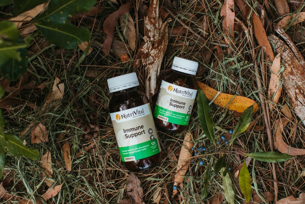 Two bottles of vitamins amongst grass, bark and leaves