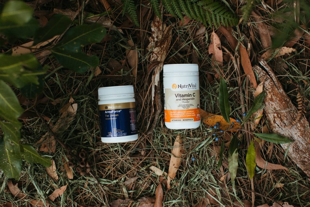 Two bottles of vitamins amongst grass, bark and leaves