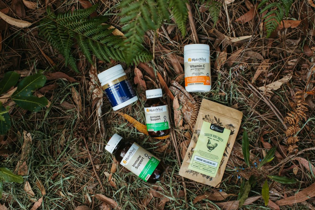 Bottles of vitamins amongst grass, bark and leaves 