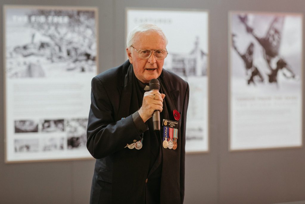 An elderly man speaking into a microphone