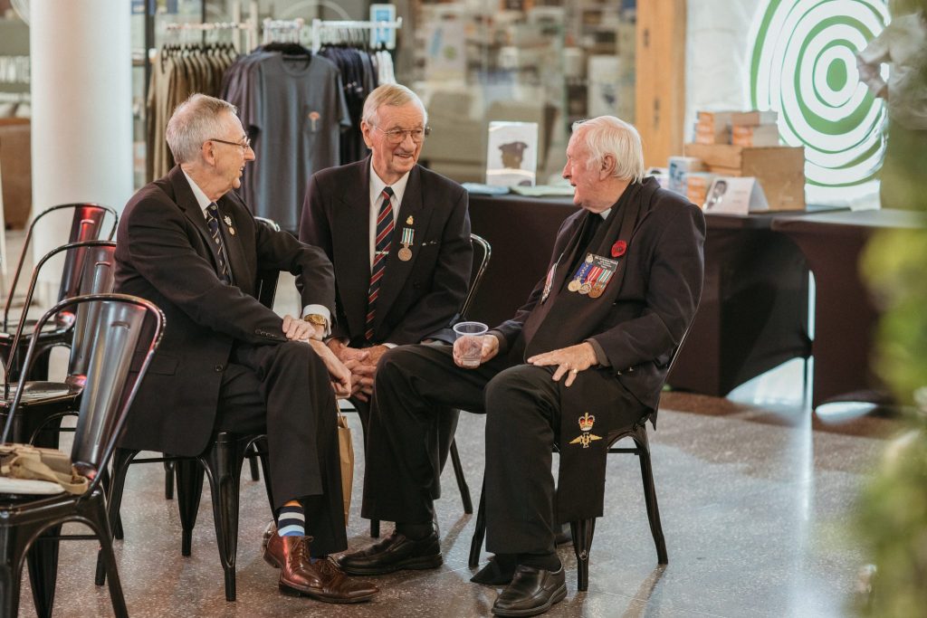 Three elderly men in suits talking and laughing 