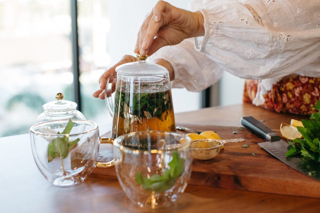 Close up of hands holding a teapot full of Moroccan Mint Tea